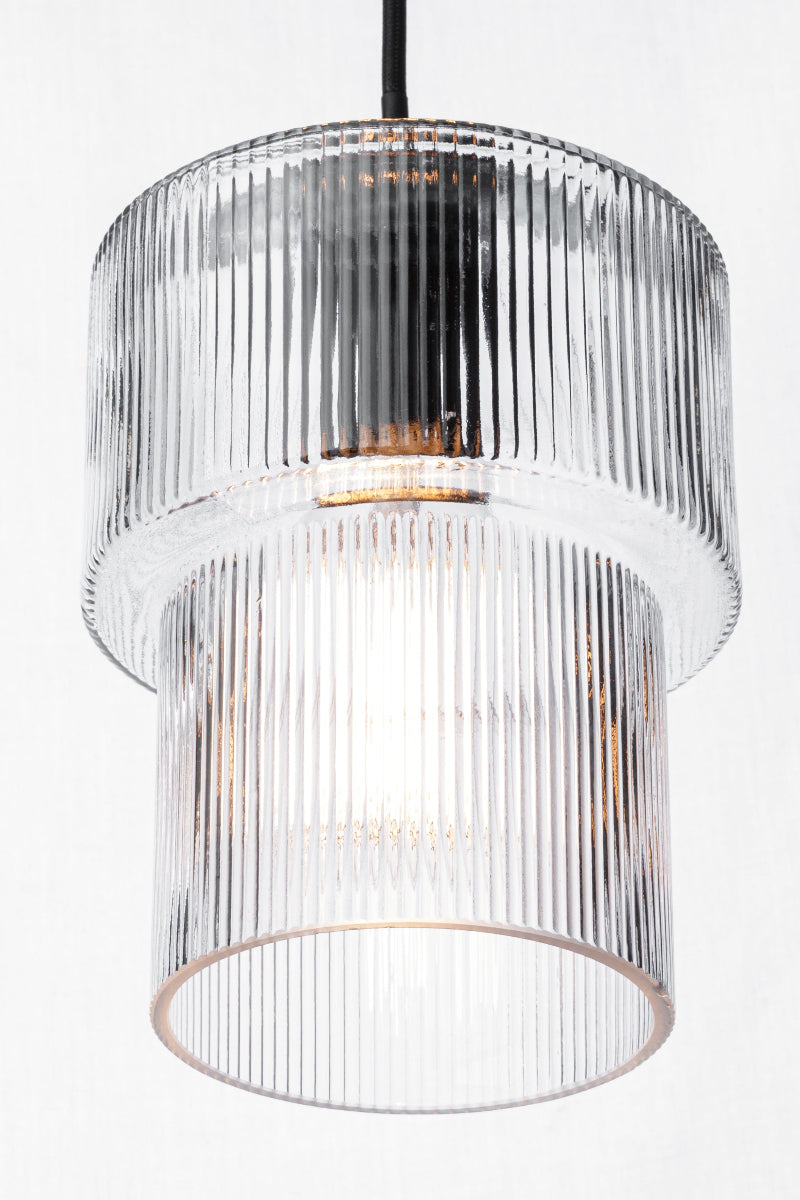 Reeded, tiered glass shade with a clear finish, paired with a black pendant cord.