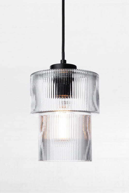 Contemporarty take on art deco style with a clear, reeded clear glass tiered shade paired with a black pendant cord. 