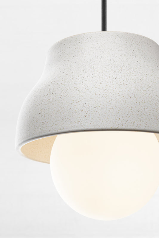 Close up of the small ceramic light grey pendant light with opal glass ball shade and black fabric cord. 