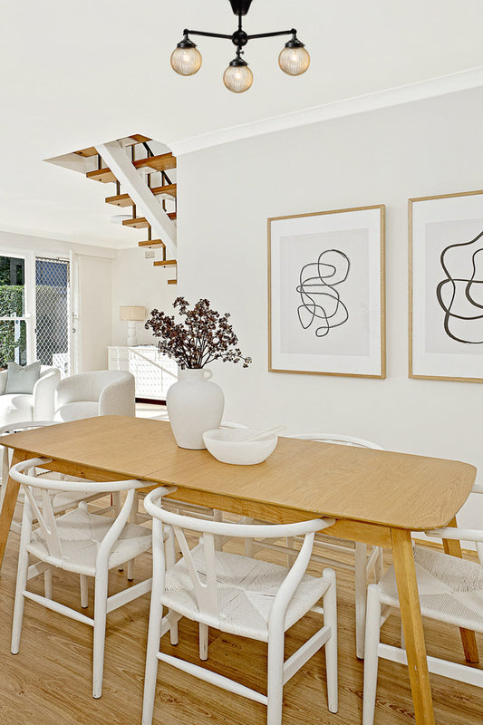 Three arm flush mount light in black with amber, reeded, glass ball shades over a scandy dining space. 