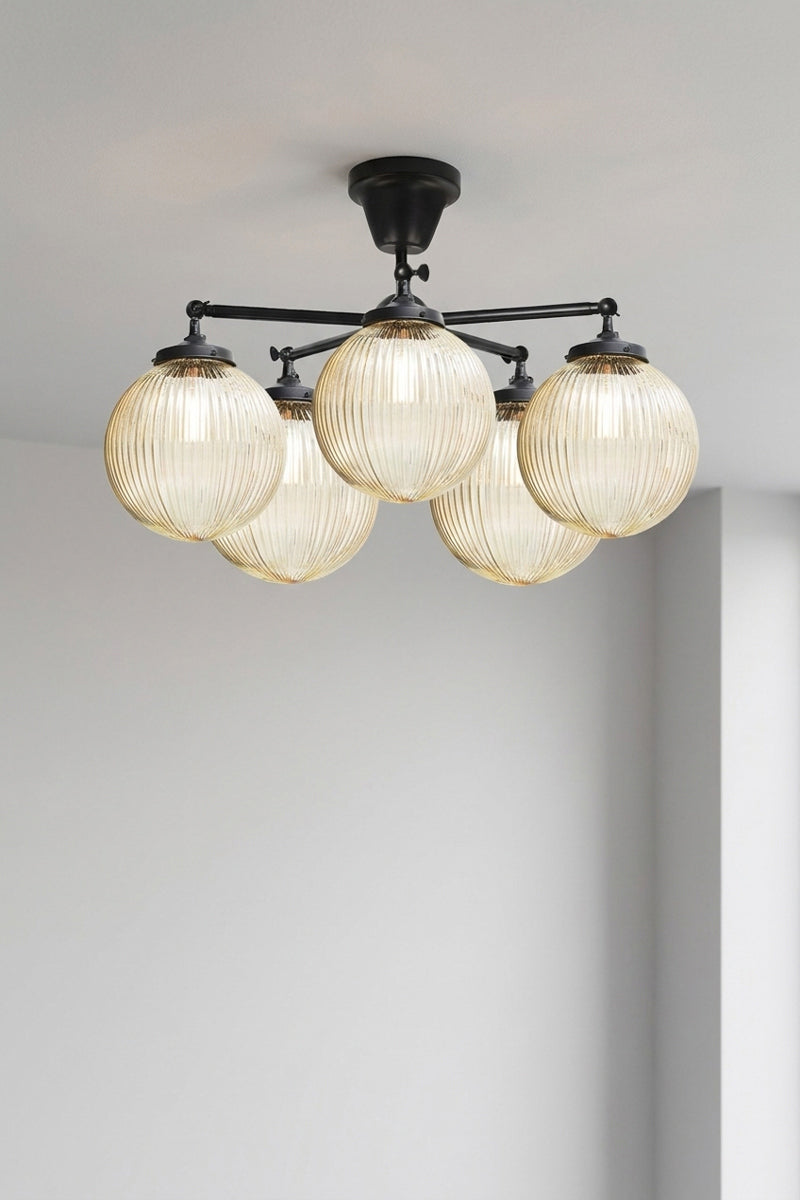 Five arm flush mount light in black with medium amber, reeded, glass ball shades. 
