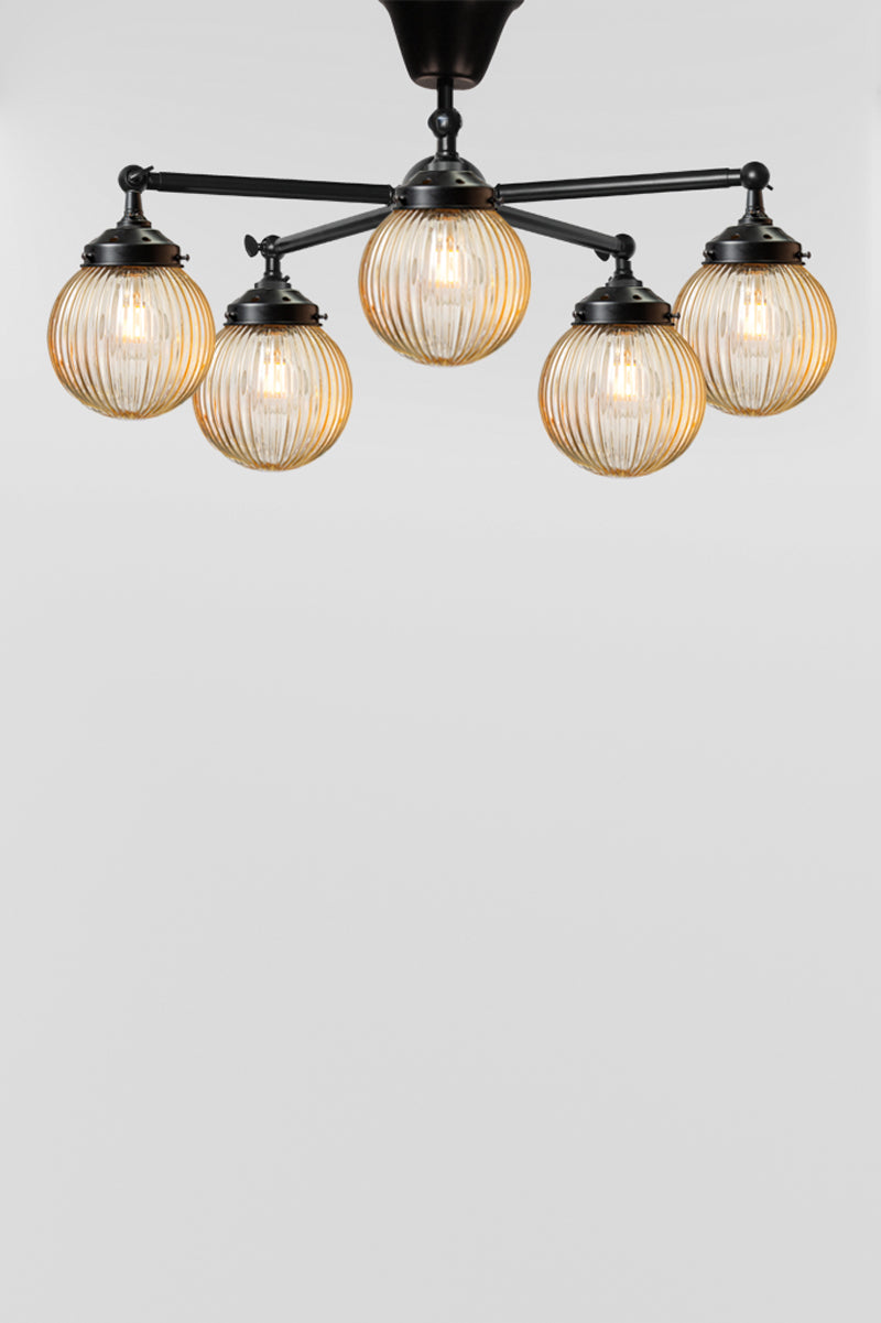 five arm flush mount light in black with amber, reeded, glass ball shades. 