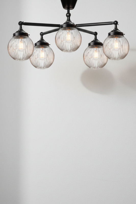 Five arm flush mount light in black with clear, reeded, glass ball shades. 