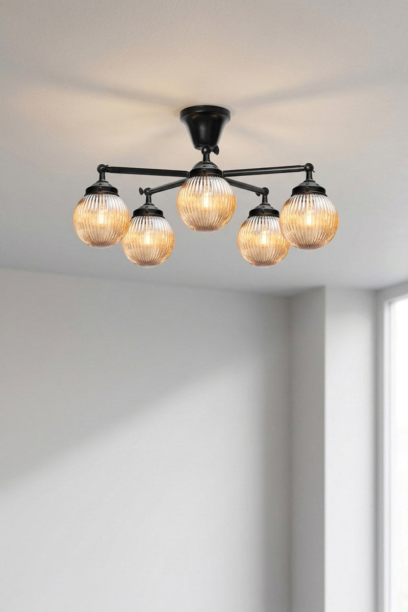 Five arm flush mount light in black with dark amber, reeded, glass ball shades. 