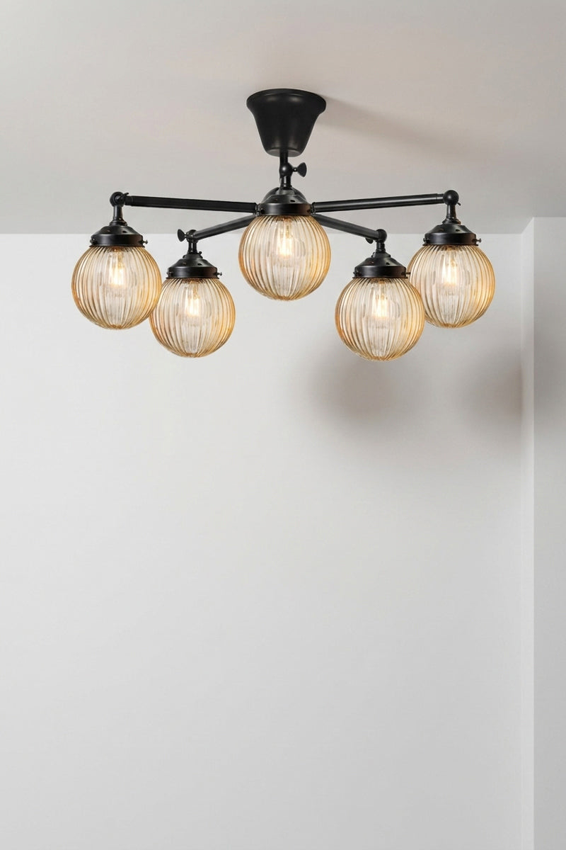 Five arm flush mount light in black with dark amber, reeded, glass ball shades. 