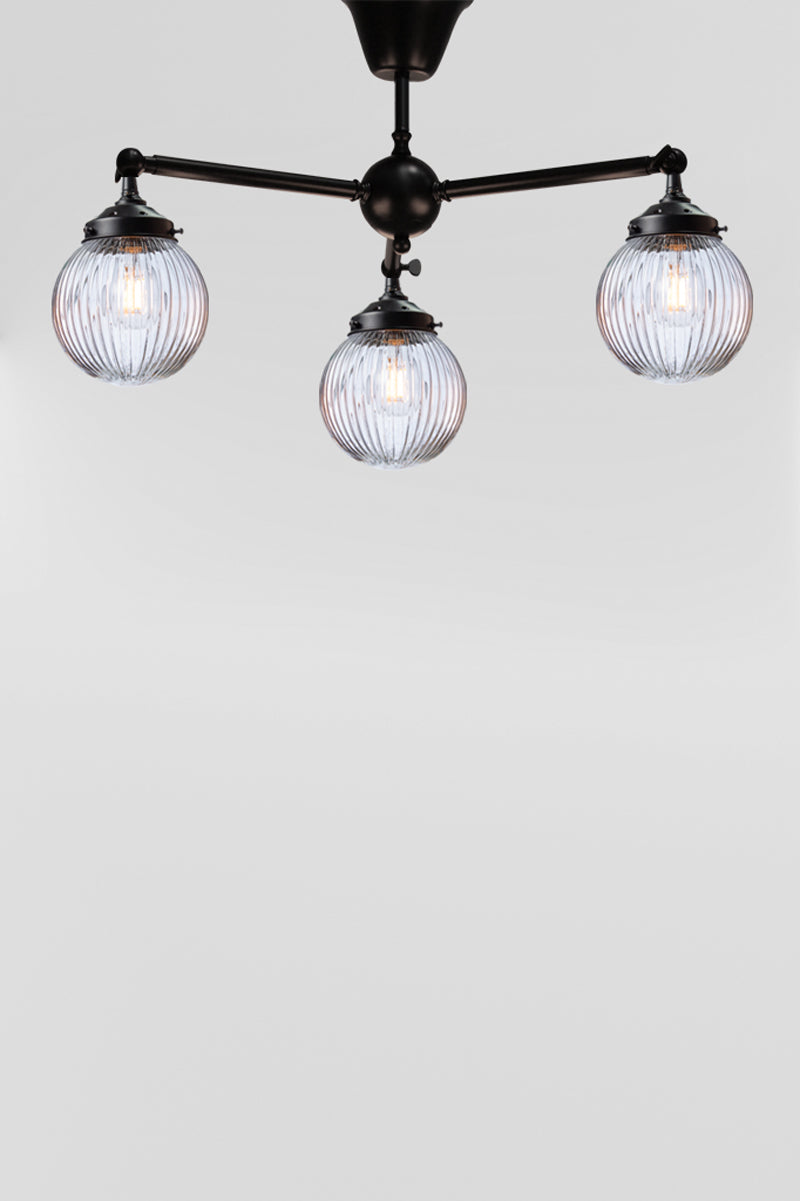 Three arm flush mount light in black with clear, reeded, glass ball shades. 