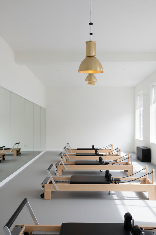 Three Gold/brass loft shades with tall gold shade caps hanging in a palate’s studio.