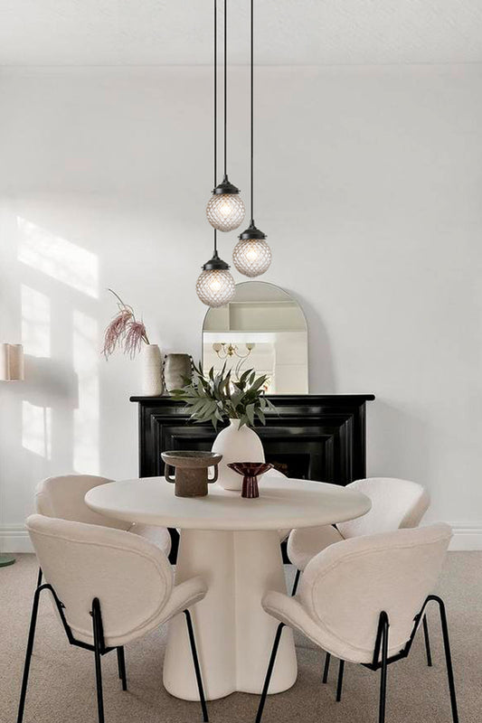 Elegant three drop black pendant fixture , with vintage, clear glass orb shades- over a mondern dining space. 