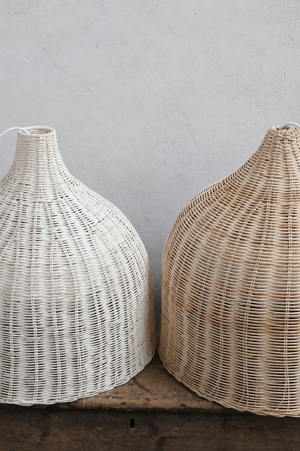 Natural and white finished wicker pendants, placed on a timber bench. 