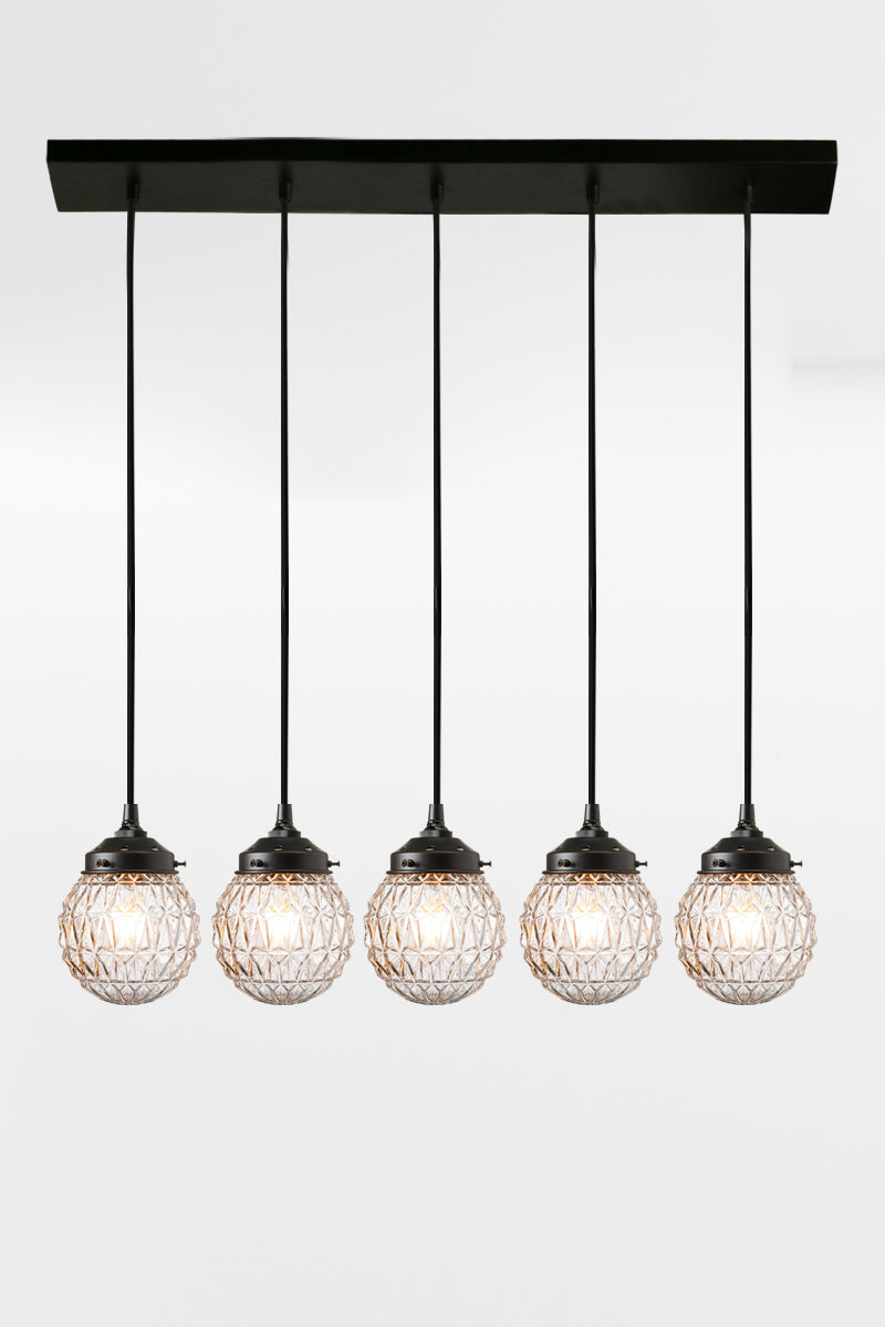 5 light mid-century modern linear light with clear textured glass and black fixture. 