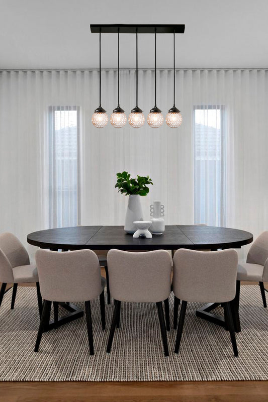 5 light mid-century modern linear light with clear textured glass and black fixtureover a dining area. 