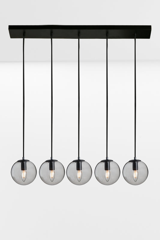 Five drop linear light with grey glass ball shades and black hardware. 