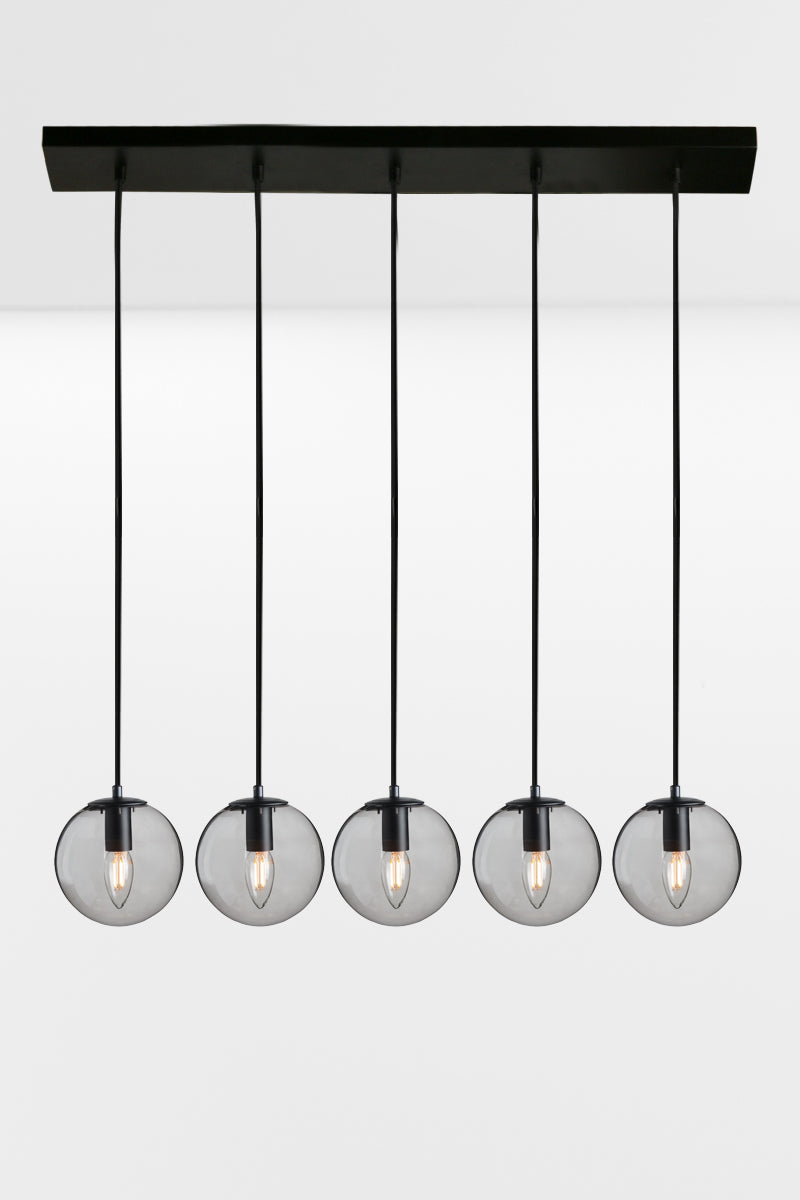 Five drop linear light with grey glass ball shades and black hardware. 