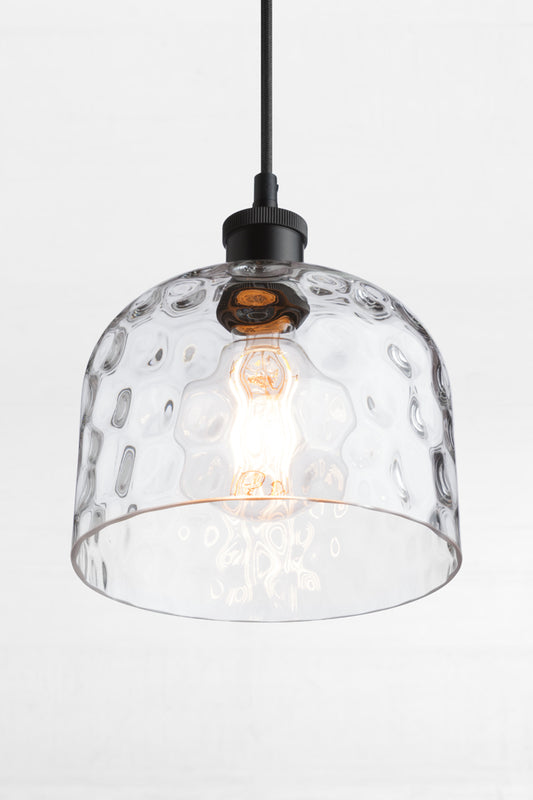 Clear glass shade with organic dimpled finish on a black lampholder, cord and clear bulb. 