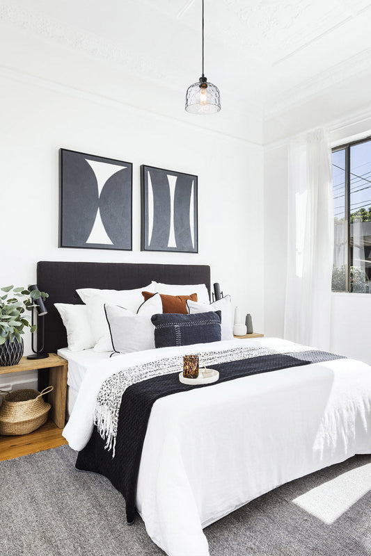 Clear dimpled clear glass shade on a black pendant cord over a contemporary black and white bedroom. 