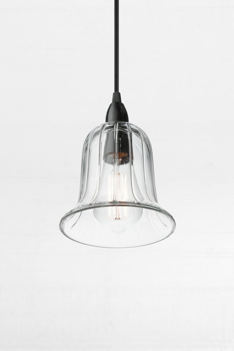 Clear glass bell shade with a black B22 pendant cord, paired with a clear tear drop bulb. 
