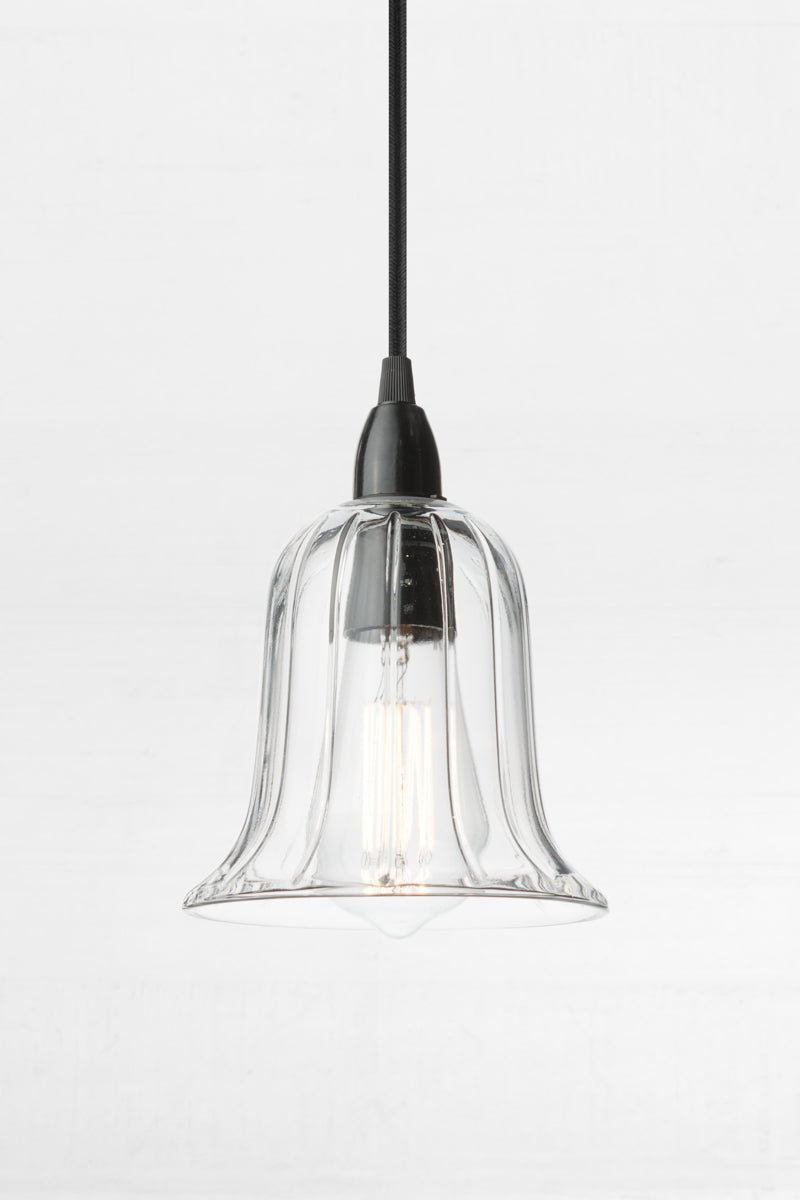  Black B22 pendant cord paired with a Clear glass bell shade with reeded detailing. 