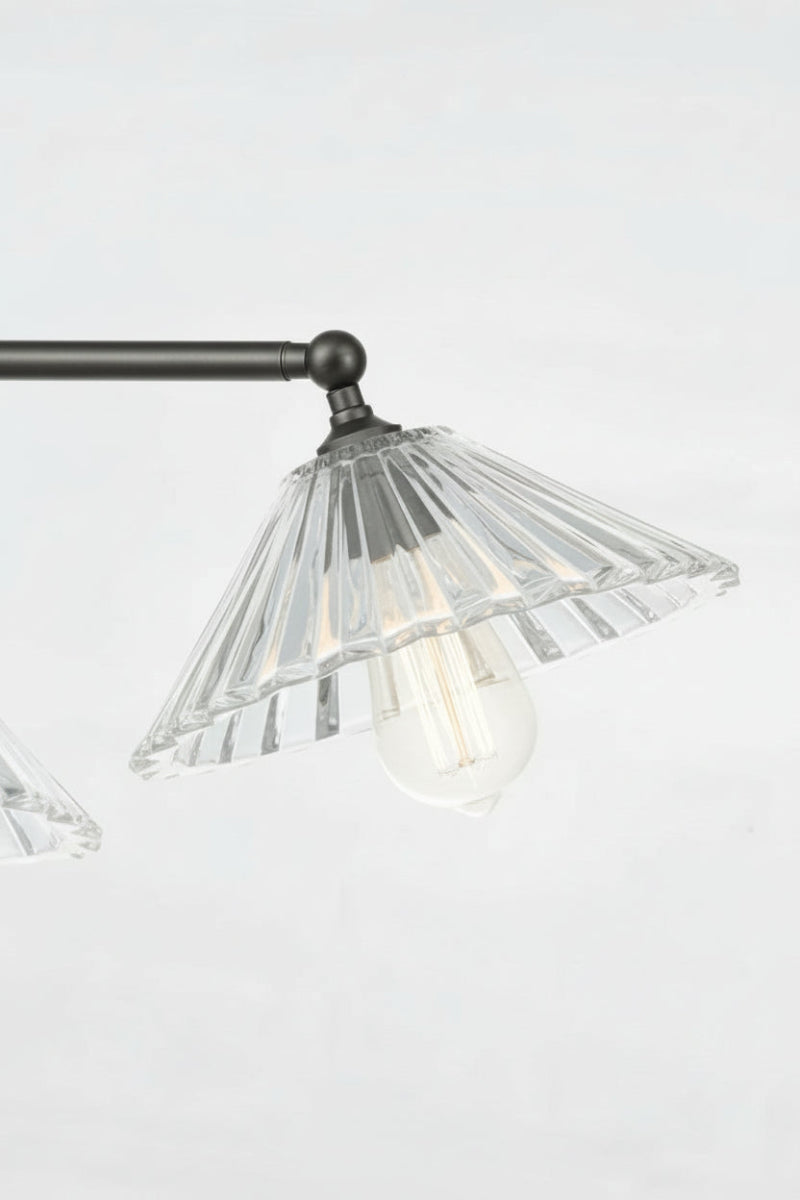 Close up of the tilted black straight arm, clear pleated glass shade and tear drop bulb. 