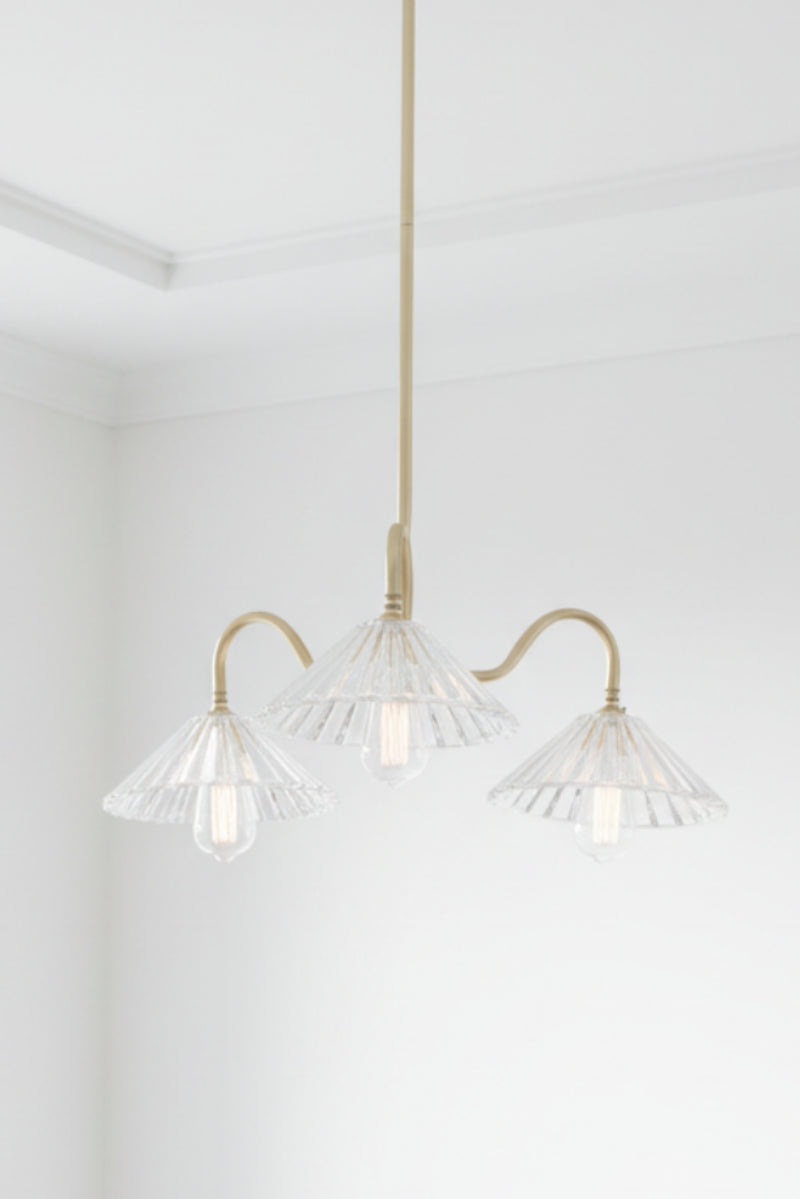 Modern chandelier with clear glass shades and gold metal accents on a white ceiling.