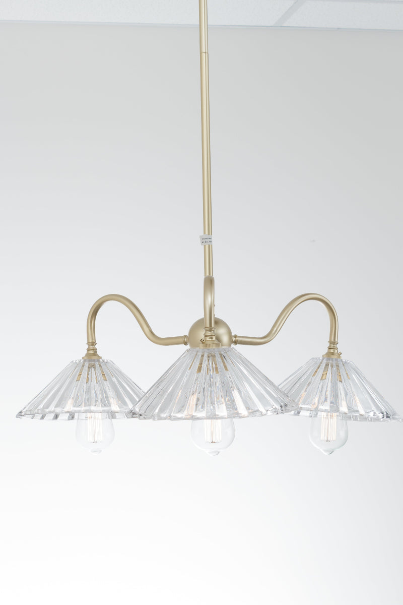 Brass colour chandelier with glass shades on a white living room
