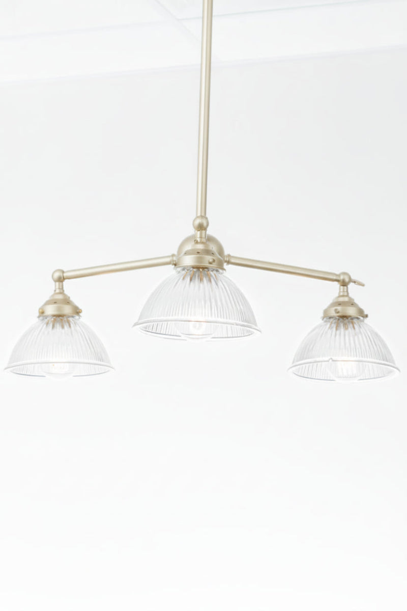 Gold/brass thre arm chandelier with clear reeded glass shades
