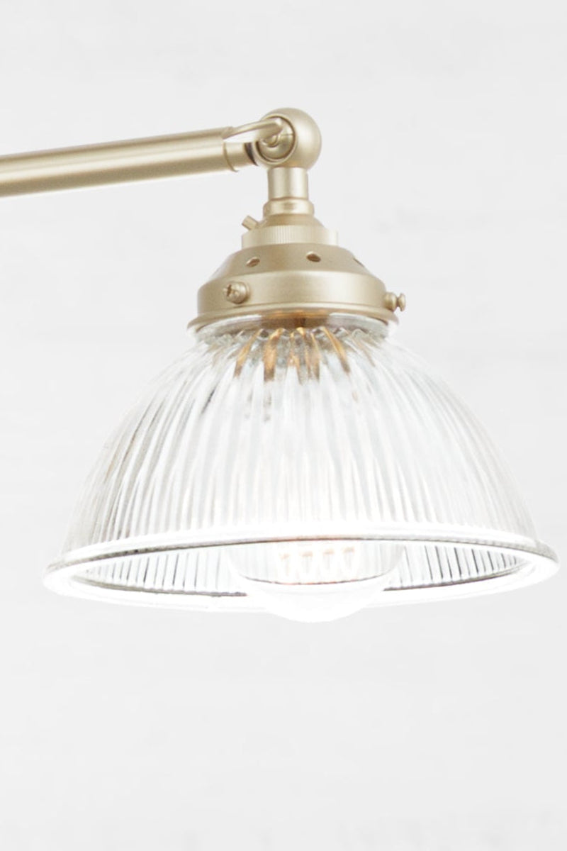 clear glass shade paired with a gold/brass finished triple arm fixture.