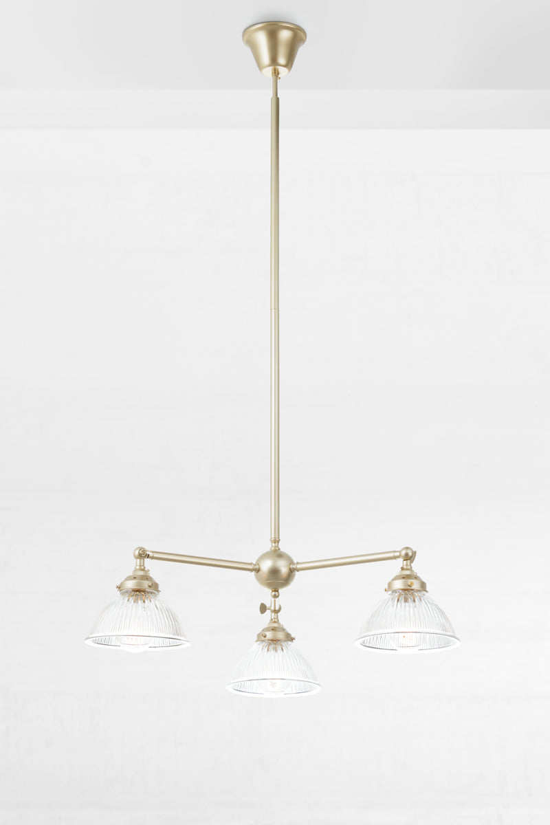 Gold/brass triple arm steel chandelier with adjustable lampholders and clear glass shades.