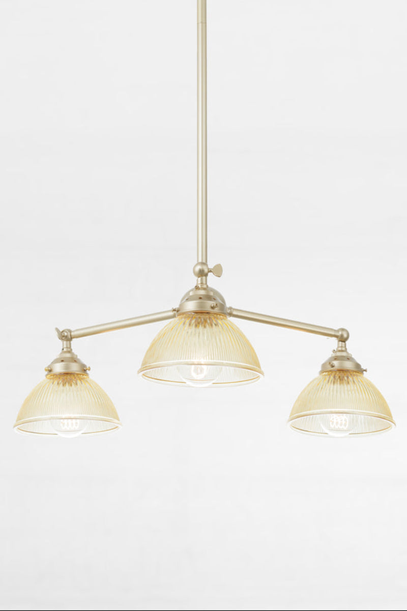 Three amber glass reeded shades with a plain edge, paired with a gold/brass finished triple arm fixture.