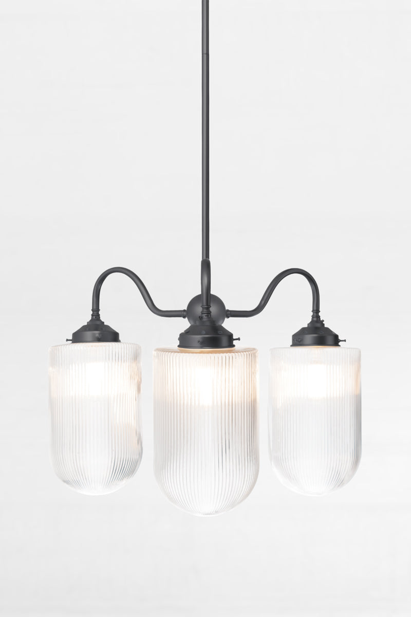 Black triple arm gooseneck chandelier with large reeded clear glass shades. 