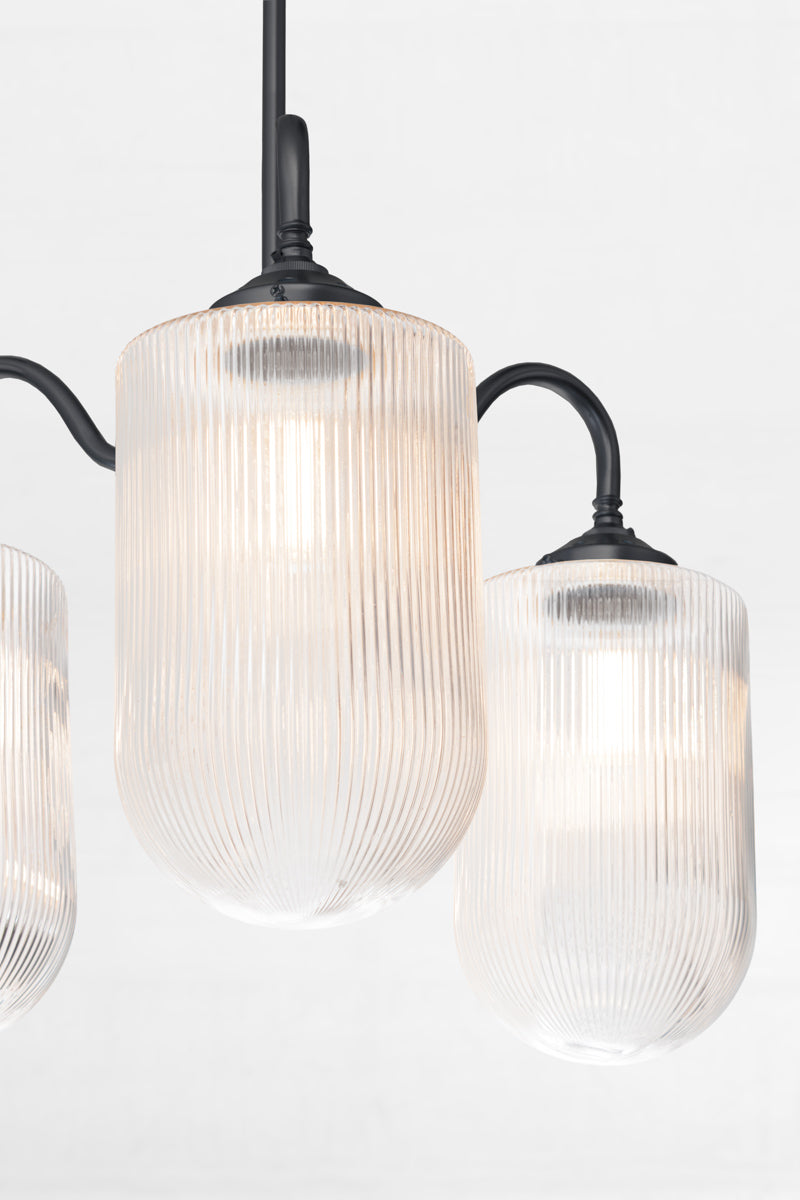 Close up of the large reeded clear glass shades on a black gooseneck arm chandelier. 
