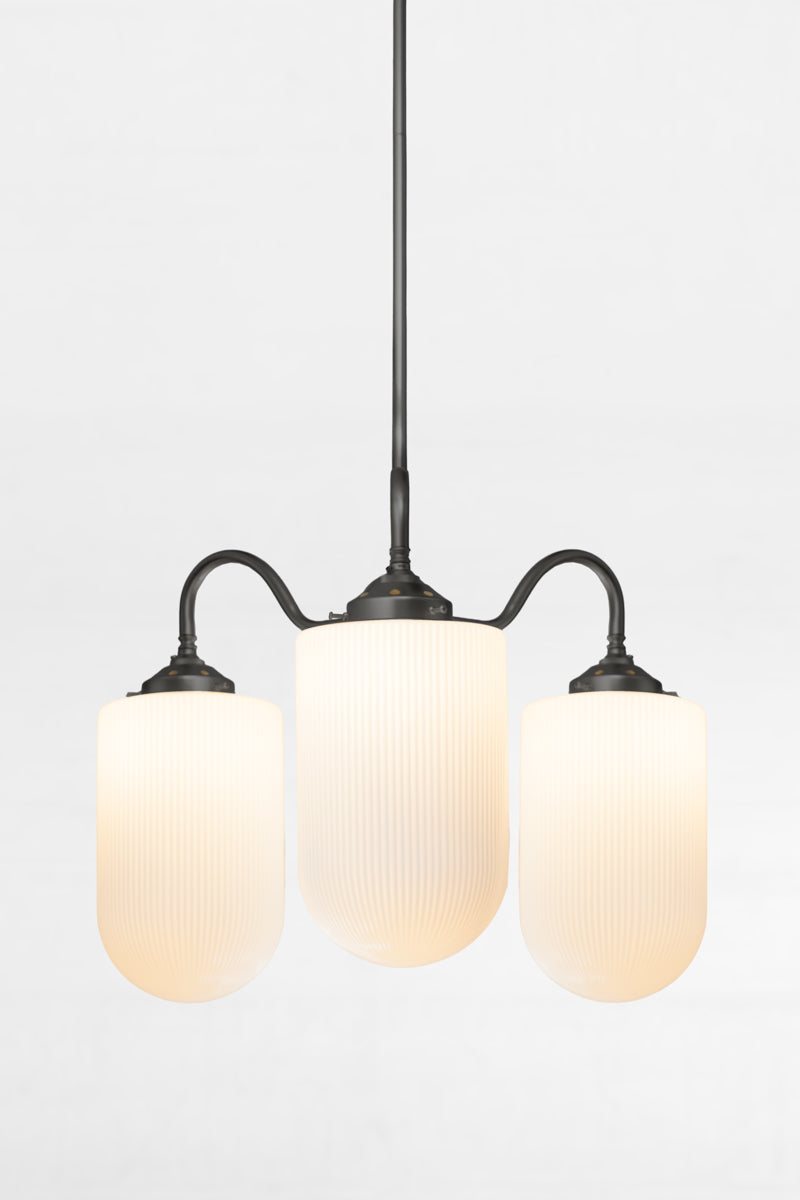 Close up of the black triple arm gooseneck chandelier with large reeded opal glass shades. 