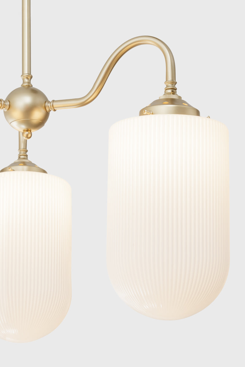 Close up of the large reeded opal glass shades on the old/brass triple arm gooseneck chandelier. 