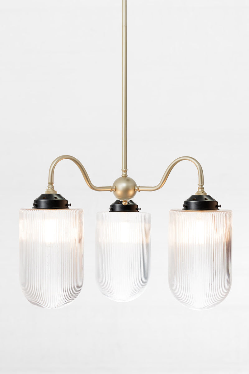 Gold/brass triple arm gooseneck chandelier with black galleries with large reeded clear glass shades. 