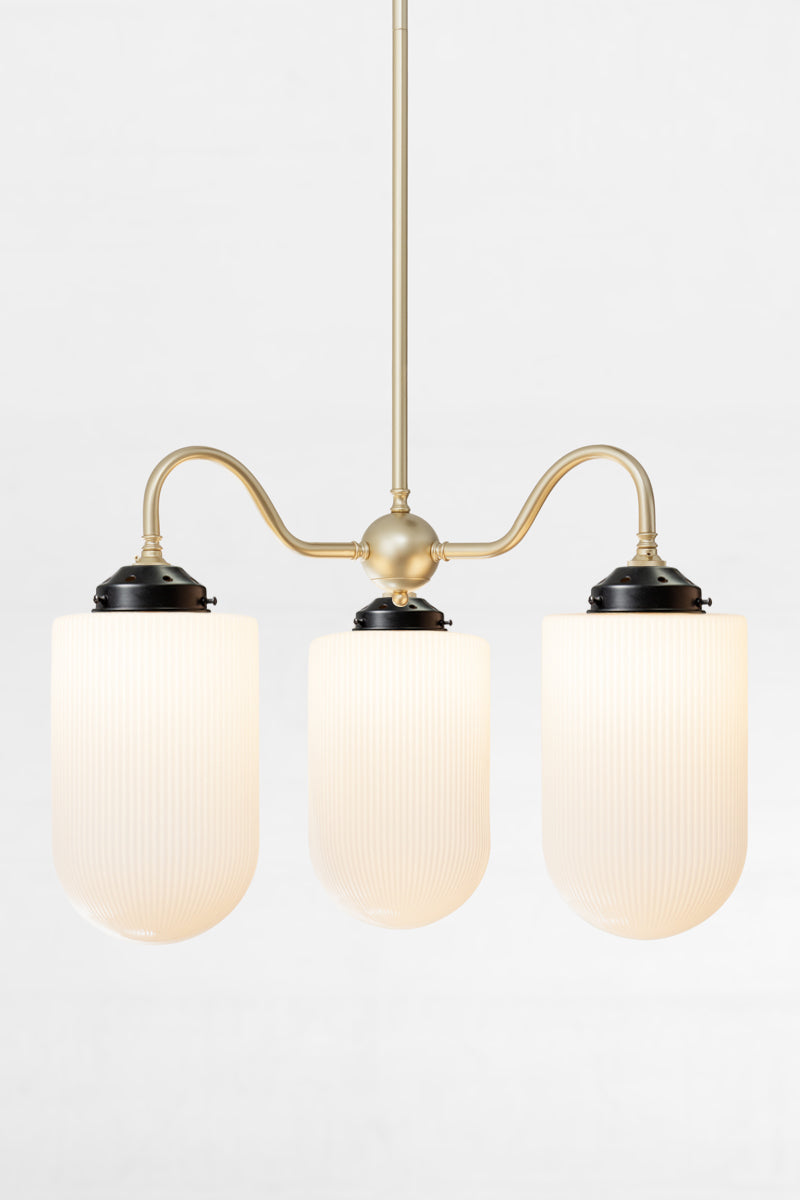 Gold/brass triple arm gooseneck chandelier with black galleries with large reeded opal glass shades. 
