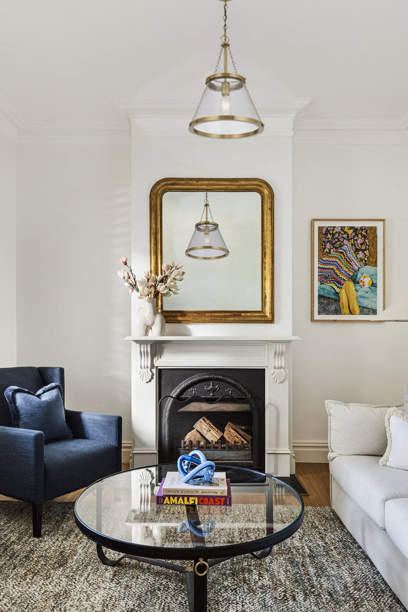 Gold/brass cone shade pendant light with textured glass in a semi formal lounge.