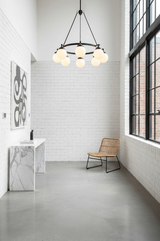 8 light black, circular chandelier with opal glass ball shades installed in a white industrial styled loft hallway. 