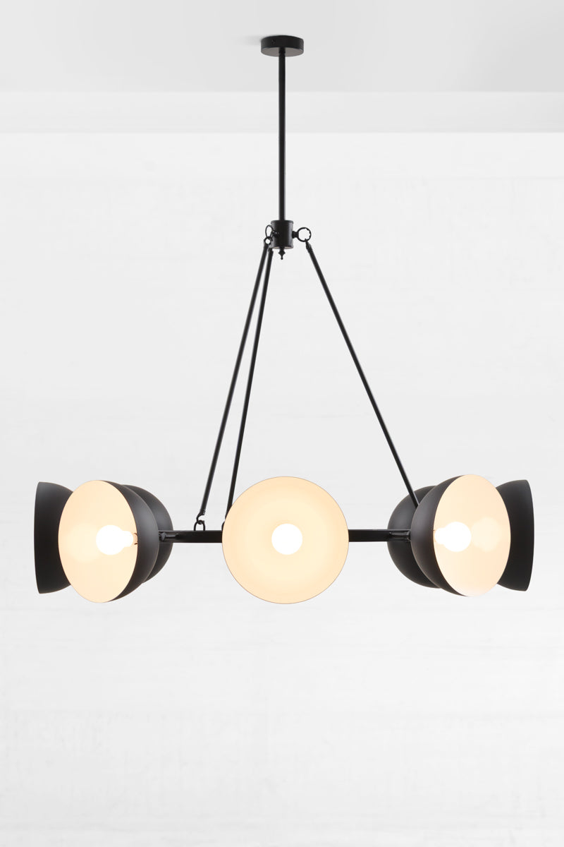 Black eight light chandelier with black dome shades facing out, showing white inner.
