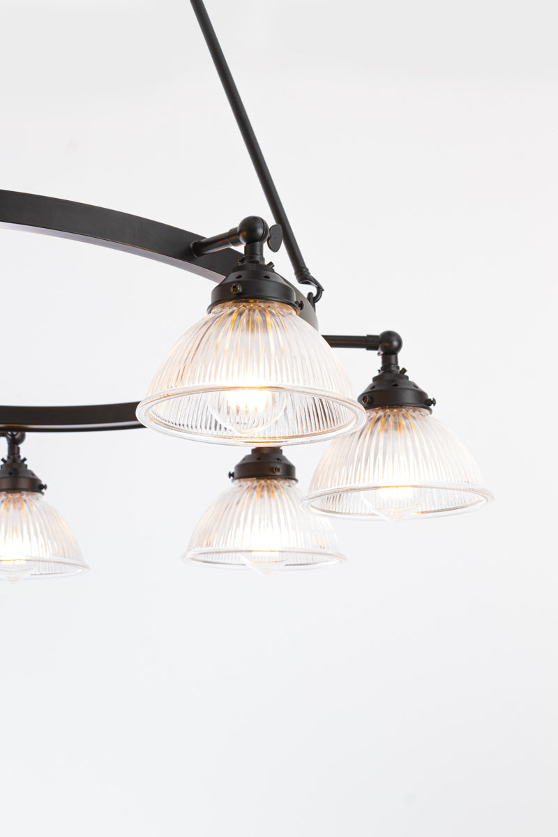 Close up of the Matt black circular chandelier's clear glass ridged shades with the lampholders facing down. 