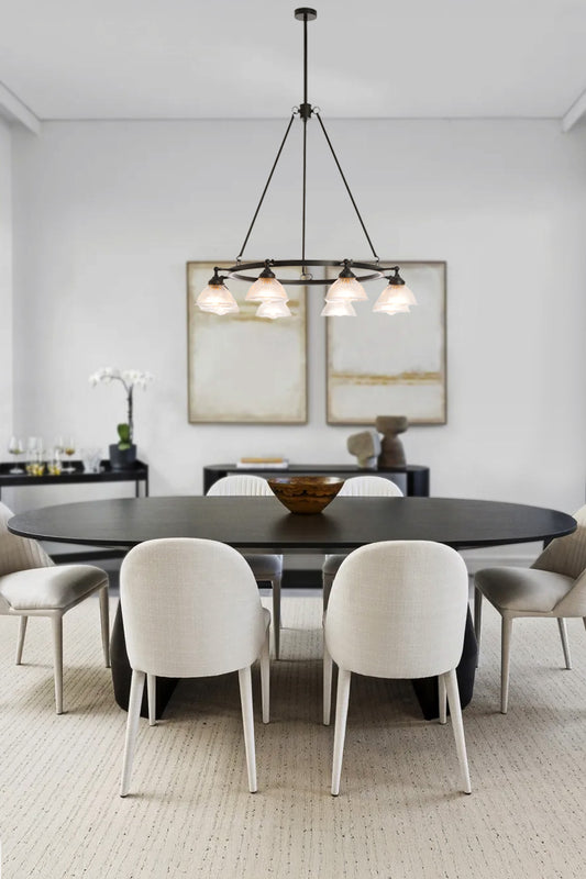 Eight light circular chandelier with clear glass ribbed shades over a sleek dining table. 