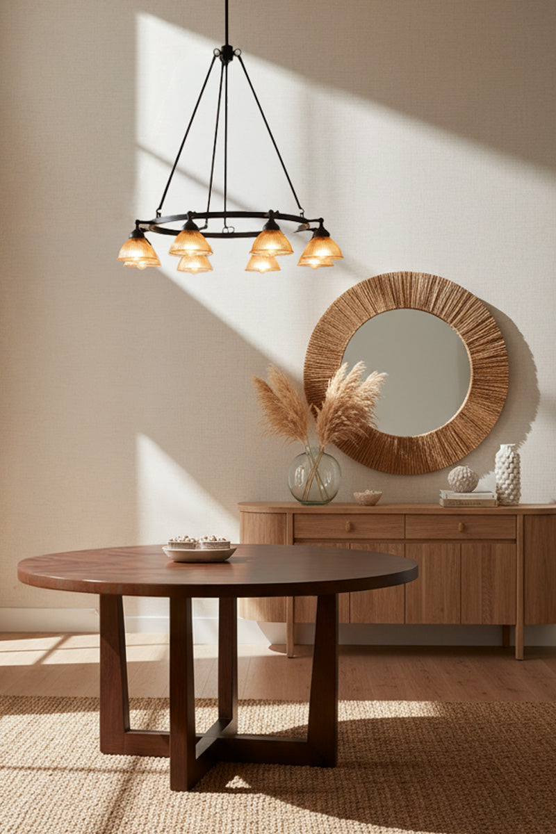 Entance hallway with round mirror and decorative elements in a room with Eight light circular chandelier with amber glass ribbed shades over a entance hall table. 