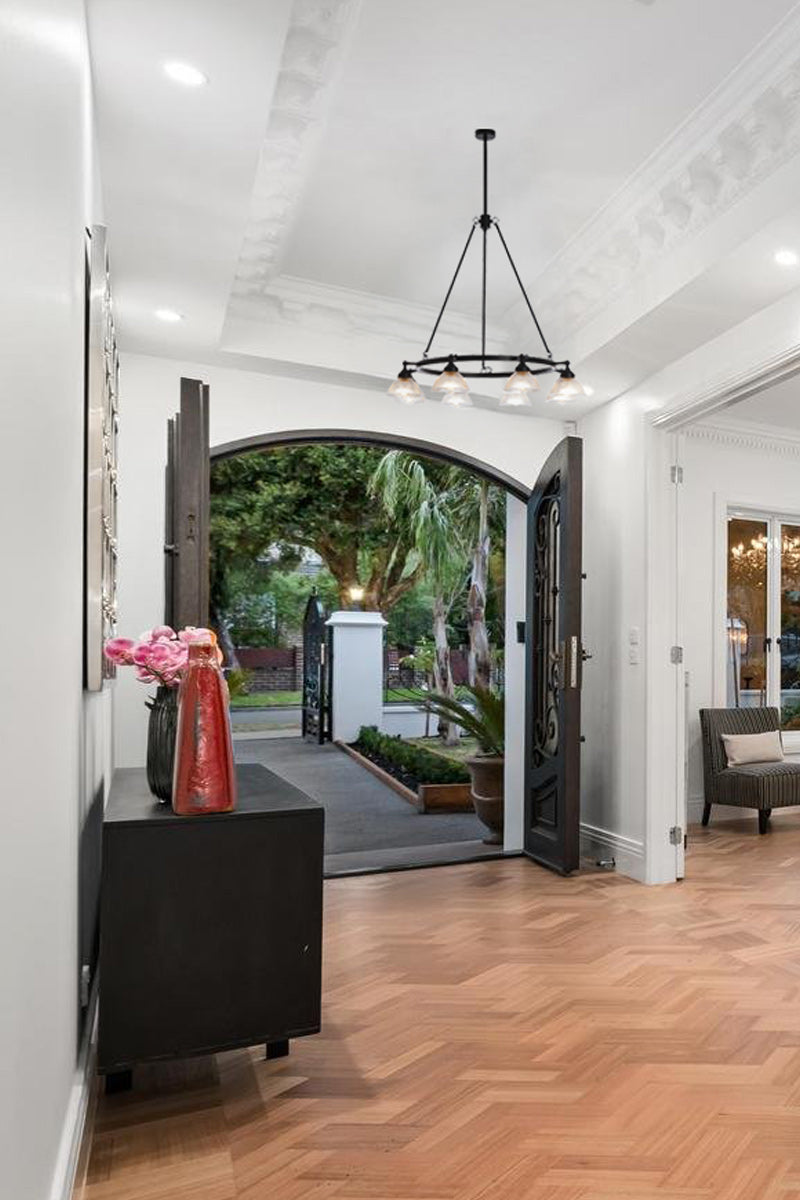 Glass shade, 8 light ircular chandelier in an entryway. 