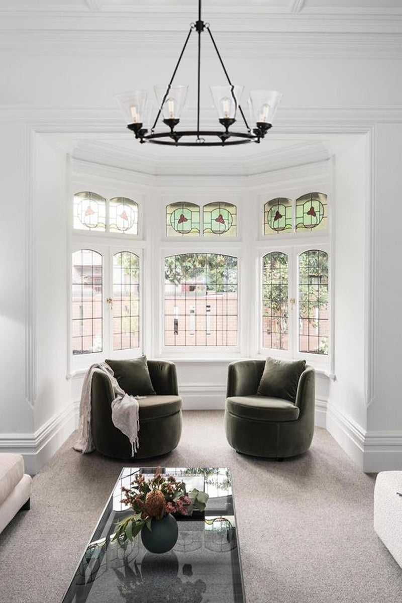 Eight light circular chandelier in black with clear glass shades in a renovated heritage home living room. 