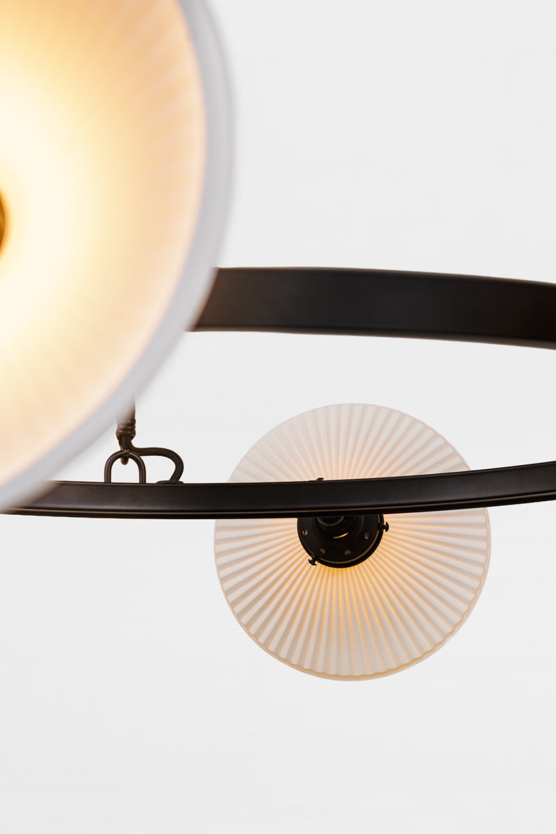 Close up of the circular chandelier in black with white ceramic shades facing out.