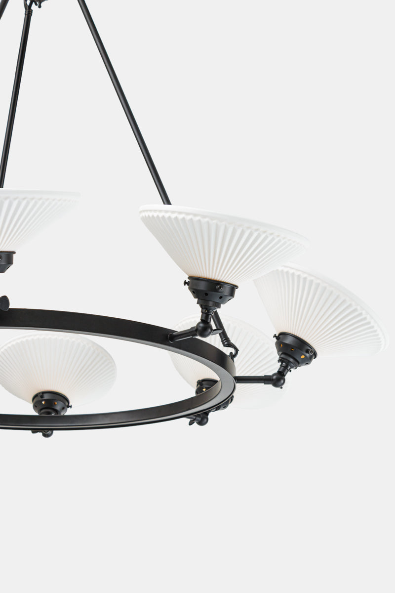 Close up of the black 8 light circular chandelier with white ceramic shades facing up. 