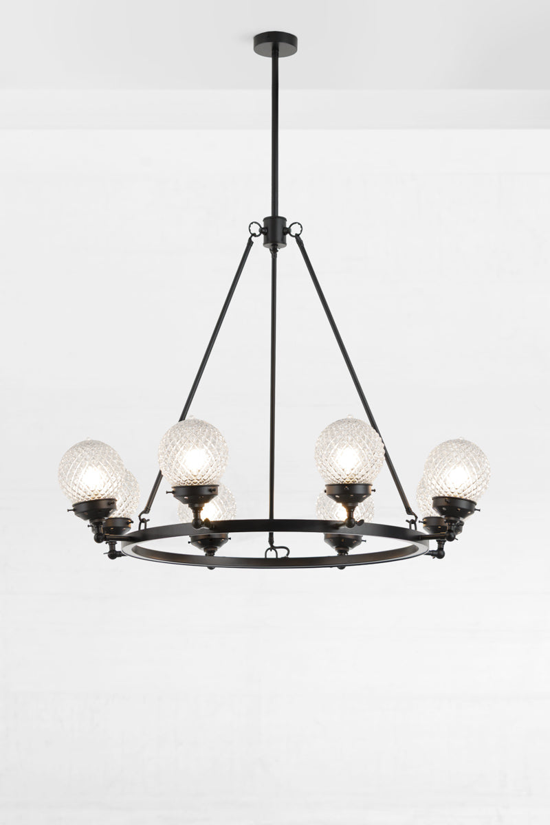 Black circular 8 light chandelier with clear glass orb shades and lampholders face up. 