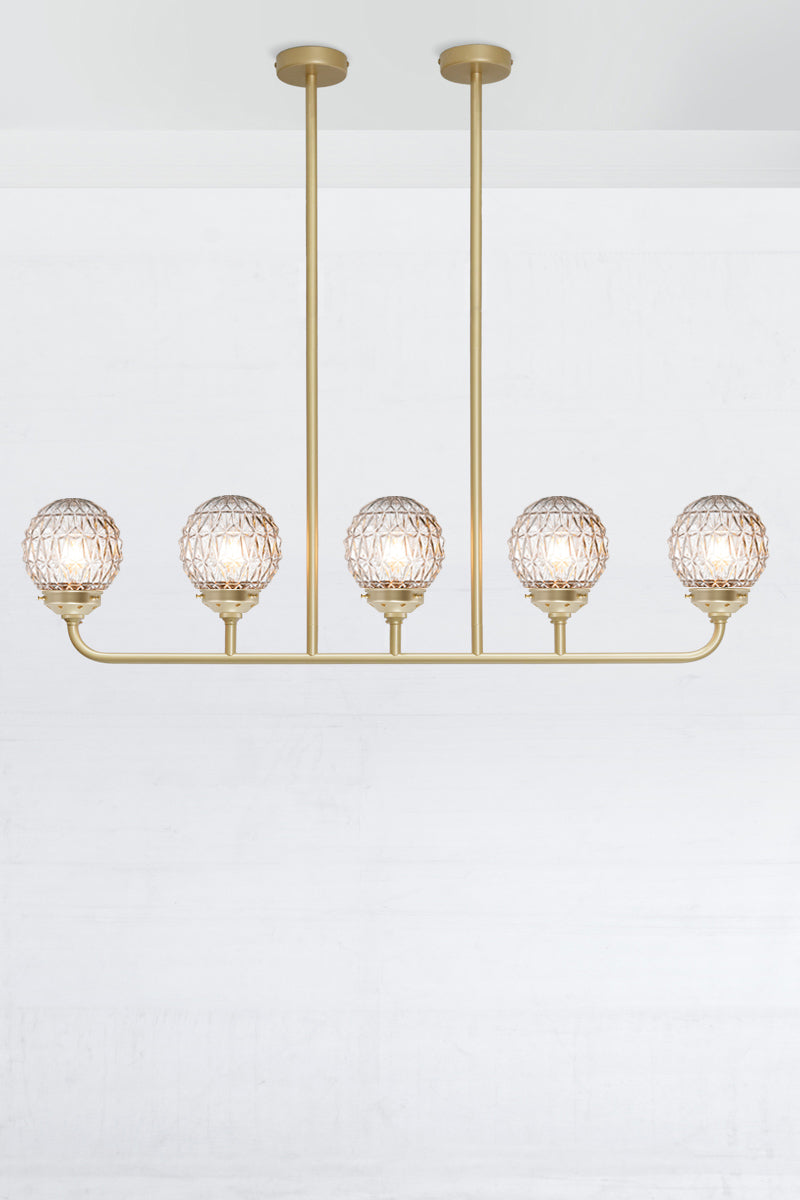 Five light linear chandelier in gold/brass with clear glass ball shades with a Geometric pattern.