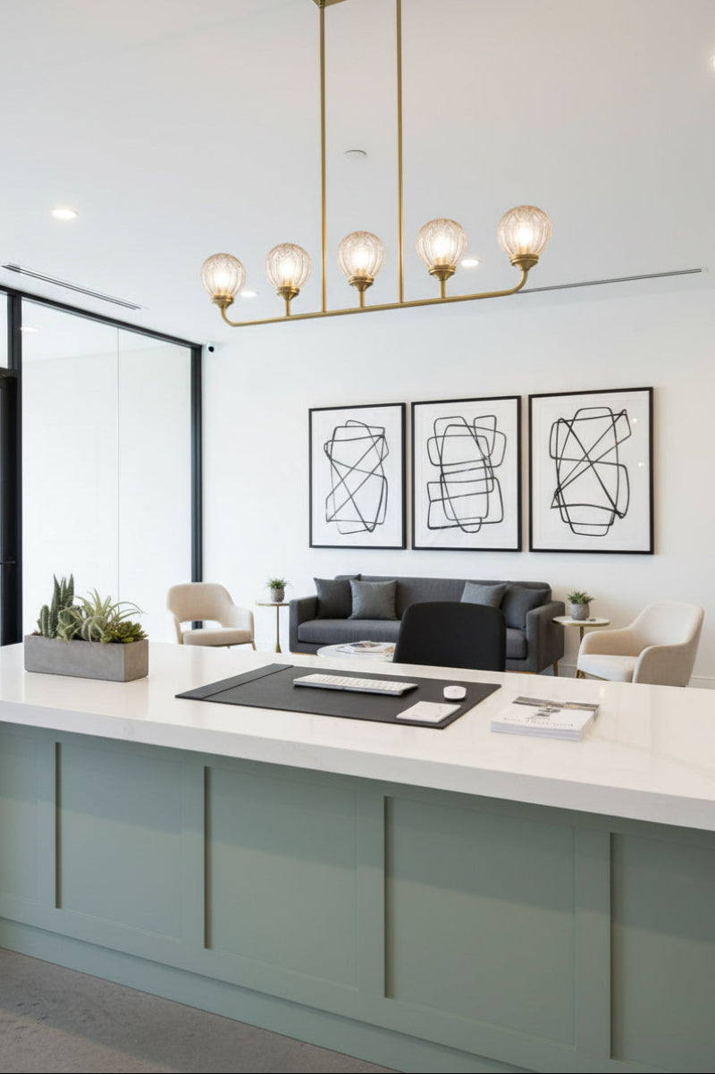 Gold/brass 5 light linear chandelier with clear glass ball shades in office showroom