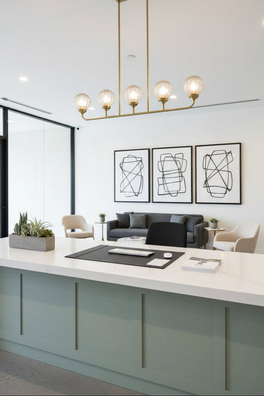 Gold/brass 5 light linear chandelier with clear glass ball shades in office showroom