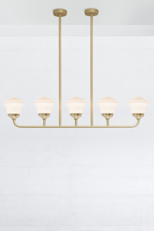 Gold/brass 5 light linear chandelier with gold/brass galleries and opal schoolhose shades. 