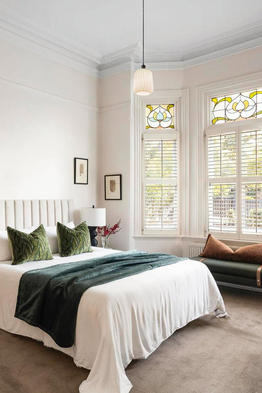 Opal shade with geometric design on a black pendant cord over a classic and light filled bedroom.